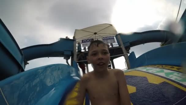 Alanya, Turkey - June 21, 2019:Cheerful view of an active small boy sliding down in Alanya resort in cloudy weather with a grey sky in summer in slow motion. - Video