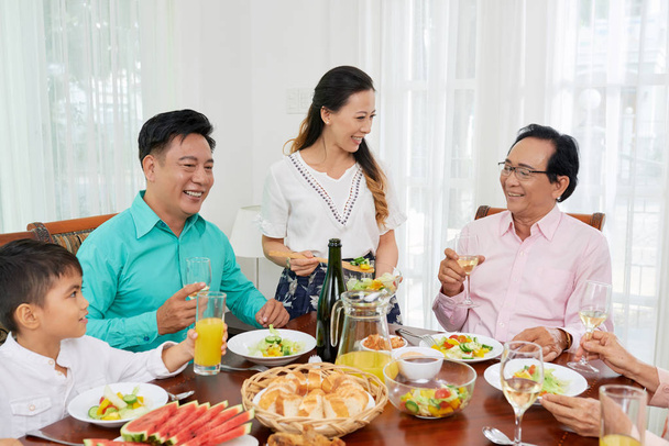 Asiática familia pasar tiempo juntos en la mesa disfrutando de la ensalada con vino y charlando en el ocio
 - Foto, imagen