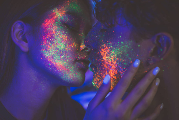 Couple kissing in the disco club with fluorescent paintings on t - 写真・画像