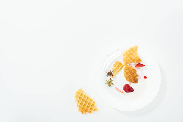 白のプレートに食べられたワッフルとイチゴのトップビュー - 写真・画像