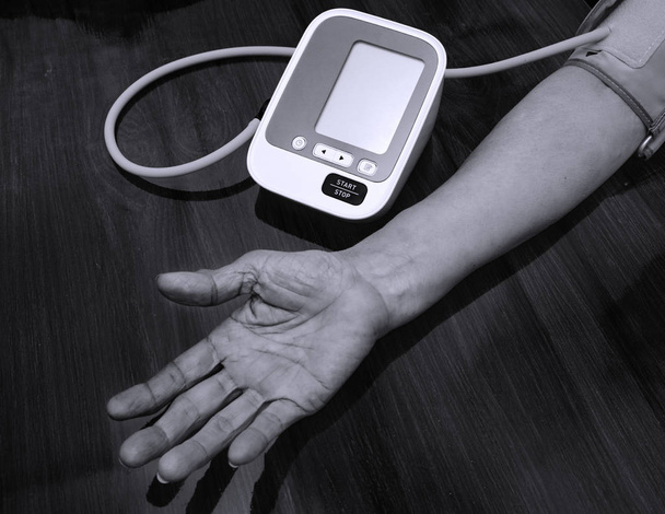 Starsza kobieta sprawdzić ciśnienie krwi. i tętno z cyfrowym pomiarem ciśnienia. Czarno-biały odcień. Szczęśliwe starzenie i koncepcja medyczna - Zdjęcie, obraz
