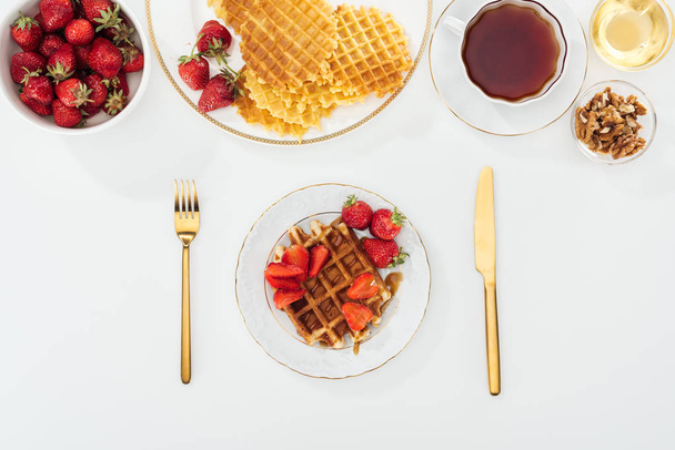 Top uitzicht van geserveerd ontbijt met wafels en aardbeien op wit - Foto, afbeelding