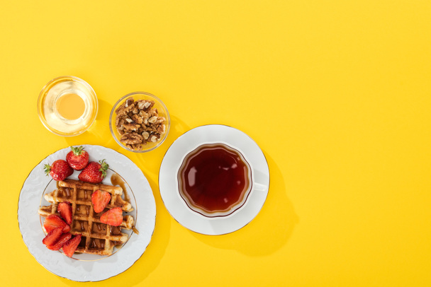 top view of waffles, berries, honey and nuts on yellow - Photo, Image