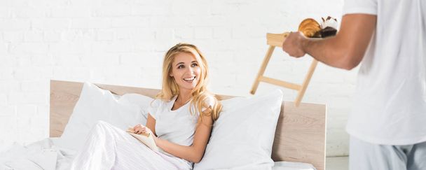 panoramic shot of man bringing breakfast to woman in bed in morning - Fotoğraf, Görsel