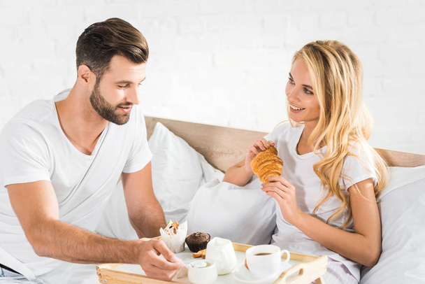 beautiful couple having breakfast in bed in morning - Foto, afbeelding