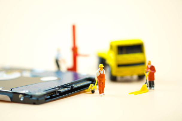 Miniature people: Workers pulling a pallet truck with circuit board moving for sent to repair. Business concept of maintenance - Photo, Image
