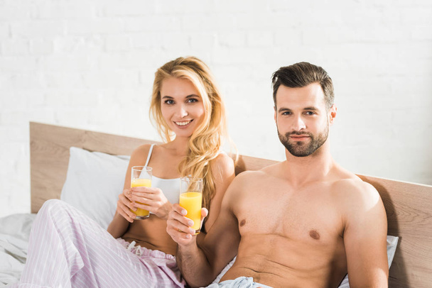 para w piżamie z sokiem pomarańczowym w łóżku rano - Zdjęcie, obraz