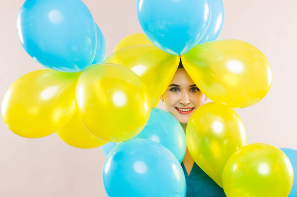 Joyful portrait of a woman with balloons of blue and yellow colors - Φωτογραφία, εικόνα