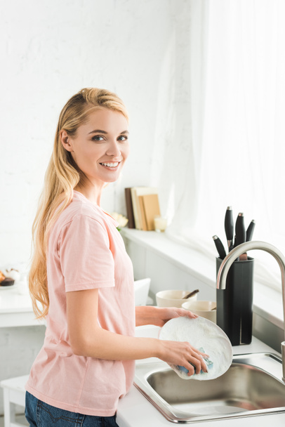 krásná šťastná žena umývání nádobí v kuchyni ráno - Fotografie, Obrázek