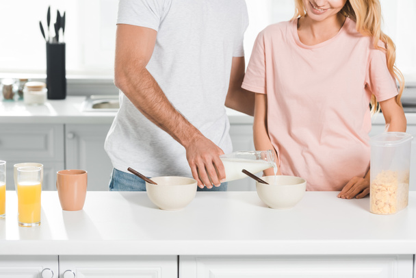 cropped view of couple with bowls of cereal during breakfast at kitchen - Fotoğraf, Görsel