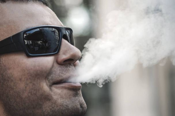 кальян курець видихає тютюновий дим крупним планом у відкритому кафе
  - Фото, зображення