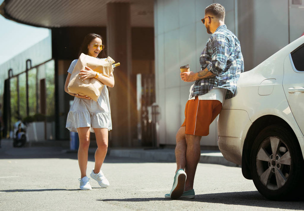 Young couple preparing for vacation trip on the car in sunny day - Фото, изображение