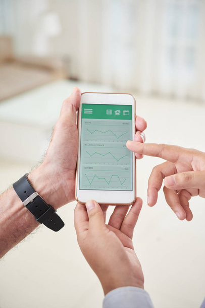 医師が高齢者のスマートフォンで健康アプリの使い方を説明 - 写真・画像