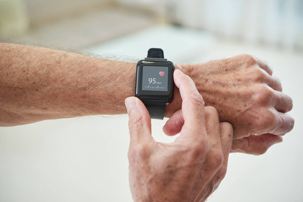 Homme senior vérifiant le pouls via l'application de santé dans sa montre intelligente
 - Photo, image