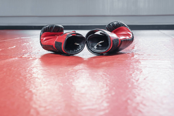 Rękawice bokserskie leżą na podłodze siłowni po treningu. - Zdjęcie, obraz
