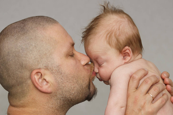 ο πατέρας με του μικρά μωρό αγκαλιά και τον φιλάει στο μάγουλο. πατρότητα, την αγάπη. - Φωτογραφία, εικόνα