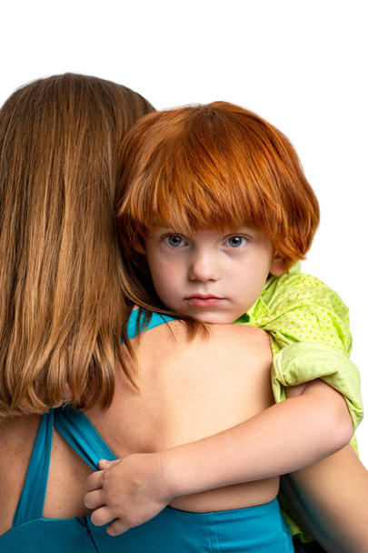 Waist up portrait of a little redhead boy gently hugging his mom - Photo, Image