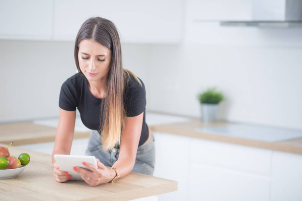 Young woman in home kitchen with tablet. - 写真・画像