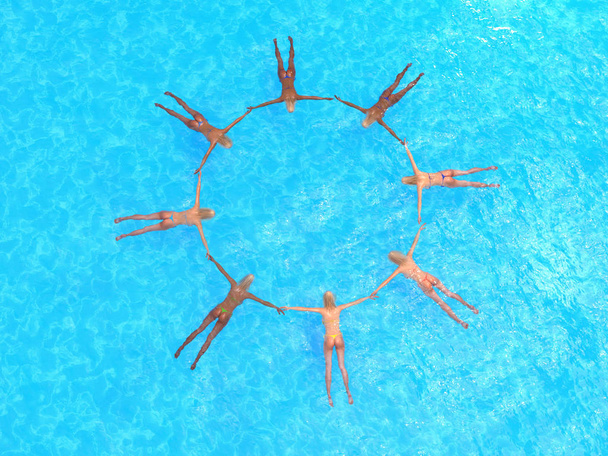 група дівчат плаває у блакитній воді, вид з повітря
 - Фото, зображення