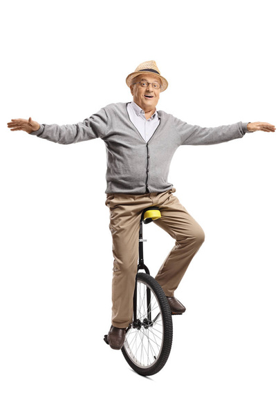 Full length portrait of an elderly man riding a mono-cycle isolated on white background - Foto, Imagem