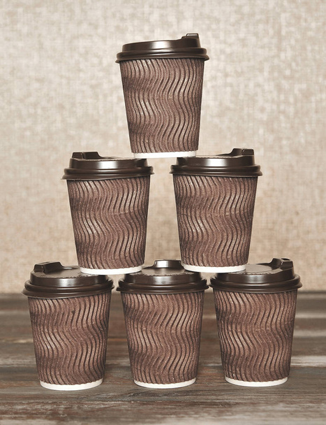 Коричневі паперові чашки для кави на дерев'яному фоні. - Фото, зображення