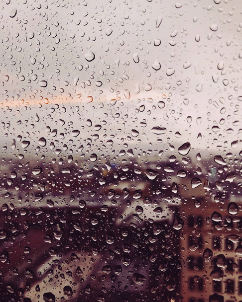 都市景観を見下ろすガラス窓のムーディーな雨滴 - 写真・画像
