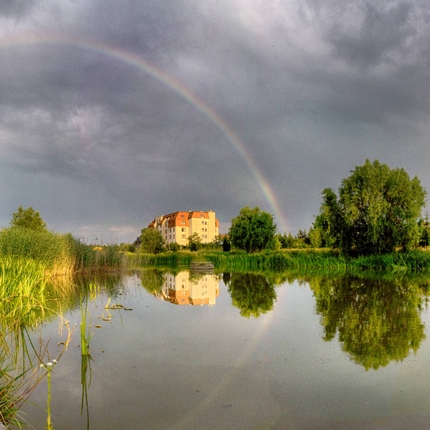 Beautiful rainbow and storm clouds over the lake, on the last day of spring, in Biskupice Podgorne near Wroclaw, Poland. - Foto, imagen