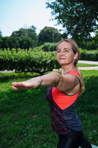 Mujer de 50 años practica yoga al aire libre
. - Foto, imagen