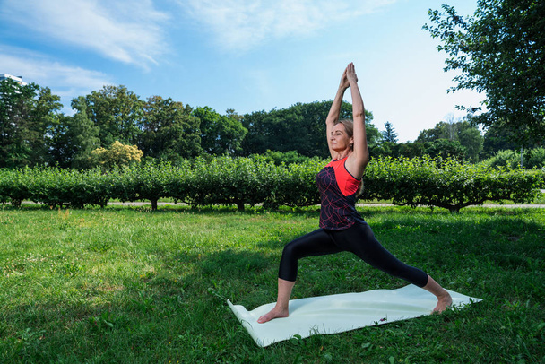 50-jährige Frau praktiziert Yoga im Freien. - Foto, Bild
