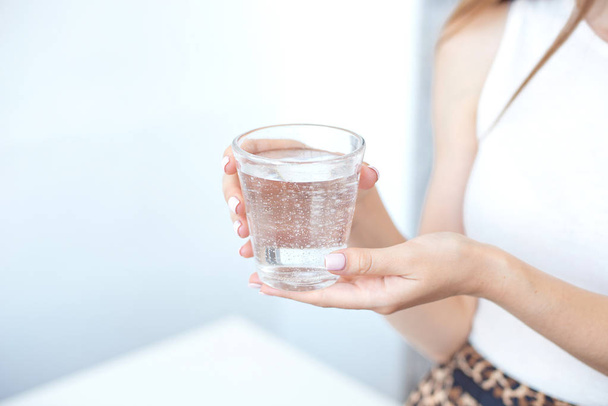 Female hands holding a clear glass of water.A glass of clean mineral water in hands, healthy drink. - Foto, Imagen