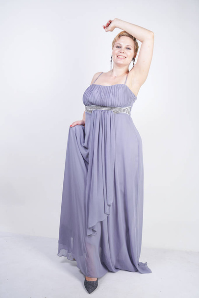elegant thick female in a grey long dress. pretty plus size woman in evening dress standing on white studio background. short hair chubby girl in gray clothes posing alone. - Photo, Image