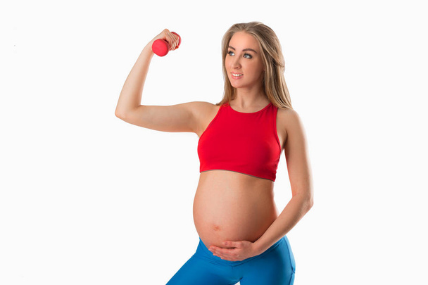 beautiful young pregnant woman with dumbbell in hand on white background - Фото, изображение