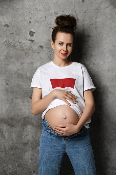 Beautiful young pregnant happy mother woman in white t-shirt posing on dark  - Foto, immagini
