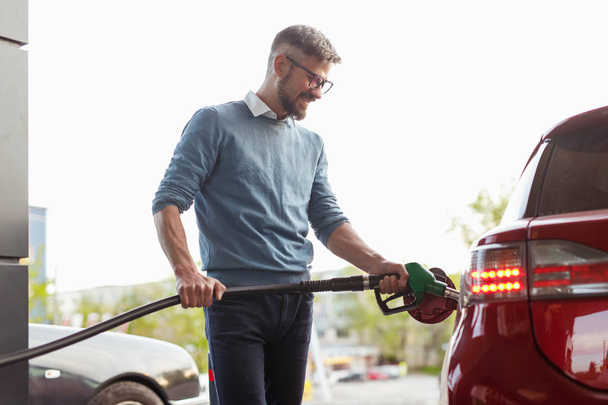Smiling man refueling car in city - Photo, Image
