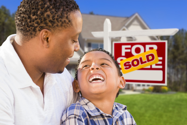 Padre e hijo de raza mixta frente a la firma inmobiliaria y la casa
 - Foto, Imagen