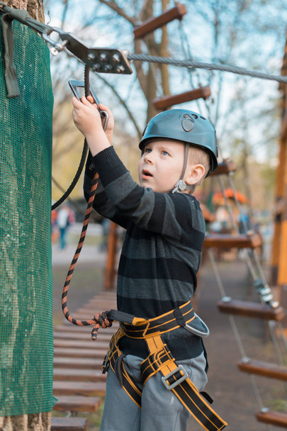 A little boy is passing an obstacle course. Active physical recreation of the child in the fresh air in the park. Training for children. - Фото, зображення