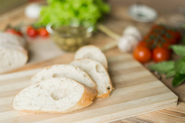 Sliced bread, ciabatta on wooden background. Preparation for the preparation of bruschetta. - Fotoğraf, Görsel