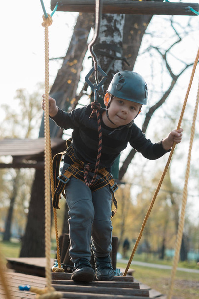 A little boy is passing an obstacle course. Active physical recreation of the child in the fresh air in the park. Training for children. - Фото, изображение