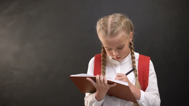 Thoughtful female kid with rucksack doing homework, having an idea, education - Záběry, video