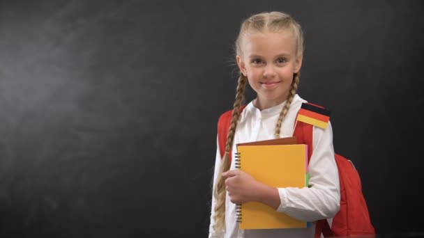 Colegiala feliz sosteniendo libros con bandera alemana, listo para aprender idioma extranjero
 - Metraje, vídeo