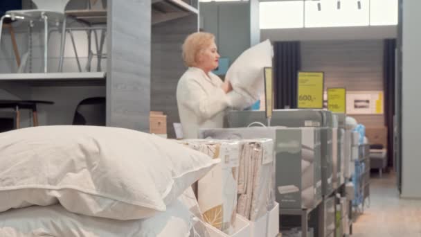 Ανώτερη γυναίκα πελάτης που επιλέγει νέο ορθοπεδικό μαξιλάρι στο κατάστημα επίπλων - Πλάνα, βίντεο