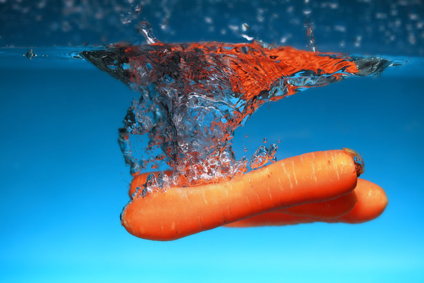 Carrot in the water splash over blue - Zdjęcie, obraz