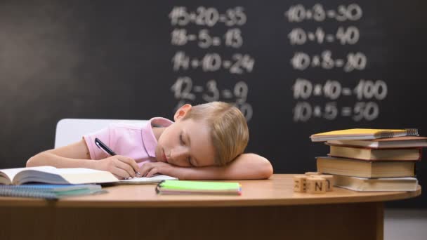 Tired schoolboy napping on desk, fallen asleep while preparing assignment - Imágenes, Vídeo