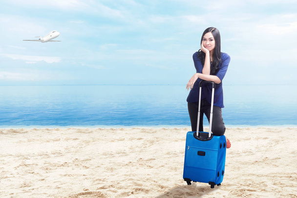 Asian woman with suitcase bag standing on the beach - Photo, image
