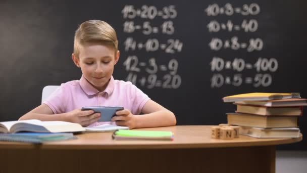 Lazy schoolboy playing videogames on phone instead of preparing task, gadget - Metraje, vídeo