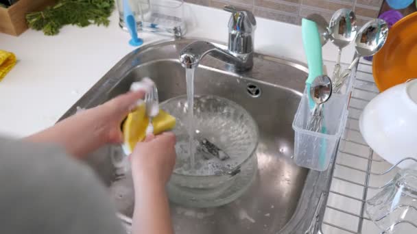女性は自宅の台所で手でカトラリーを洗っている. - 映像、動画
