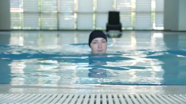 Vrouw is zwemmen aan de zijkant van het zwembad kijken naar camera en glimlachend. - Video