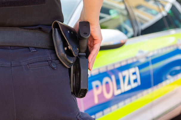 Női rendőr tartja a kezét a fegyverét. Polizei a német szó a rendőrség - Fotó, kép