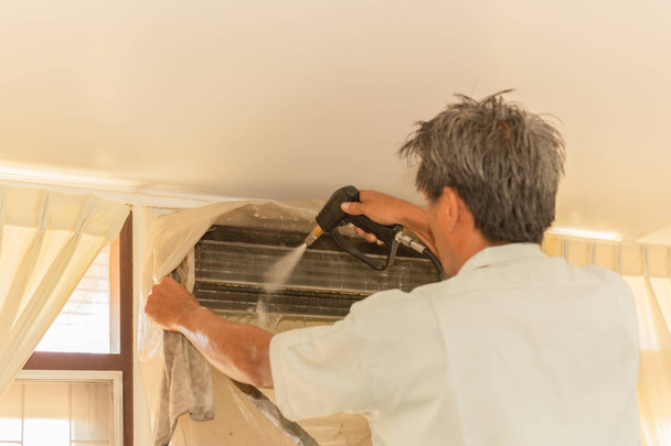 Operaio pulizia parete condizionatore d'aria con pompa a getto d'acqua ad alta pressione a casa
. - Foto, immagini