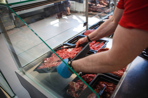 Raw meat in trays in the window of a butcher shop. The seller puts the meat on display in black trays - Foto, Imagem